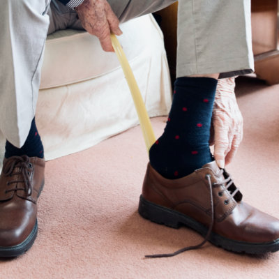 An elderly man putting on shoes